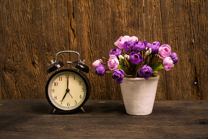 Çalar saat ve masanın üzerinde çiçekler