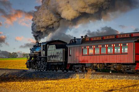 A steam locomotive releasing smoke at dawn