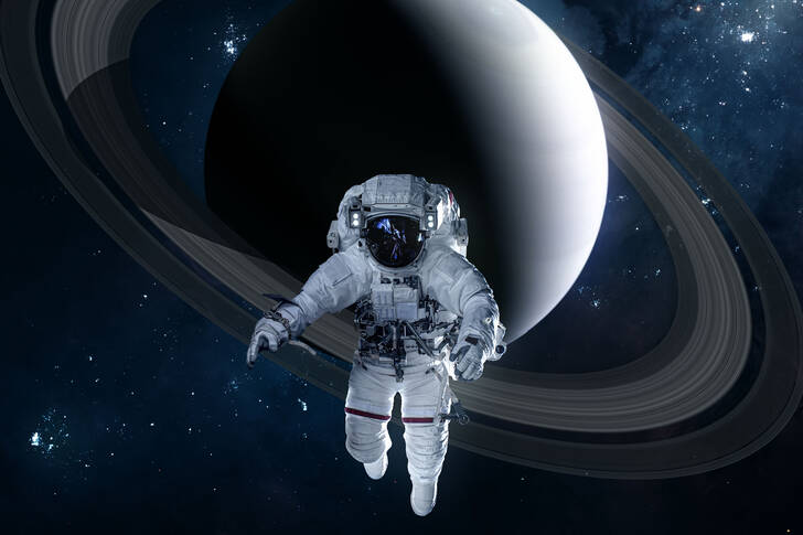 Astronautti, taustalla Saturnus