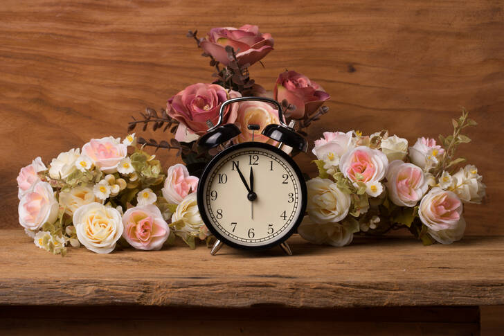 Relógio despertador com flores na mesa