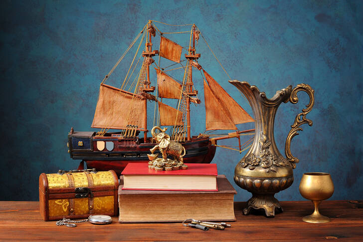 Barca a vela, brocca e libri sul tavolo