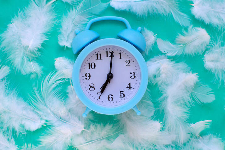 Blue alarm clock and white feathers