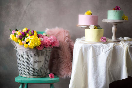 Cesta con flores y pasteles sobre la mesa.