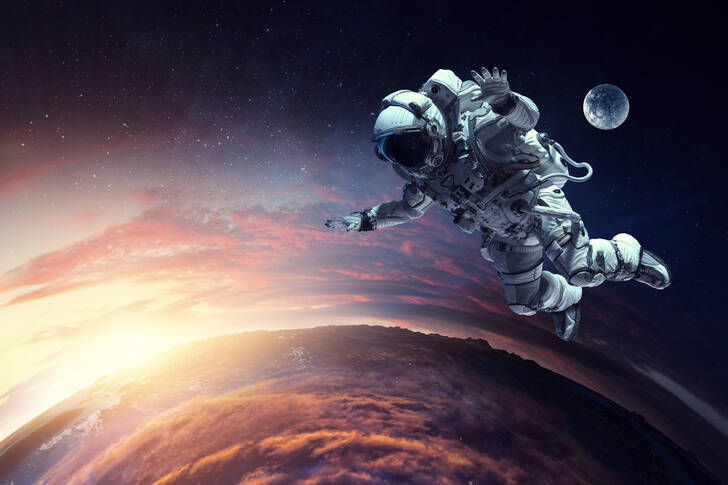 An astronaut against the backdrop of the Moon and Earth