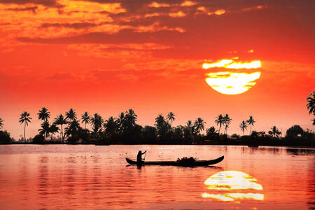 Pescador em um barco ao pôr do sol