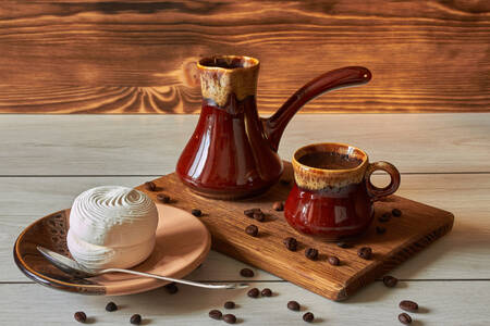 A cup of coffee with a cezve and marshmallows