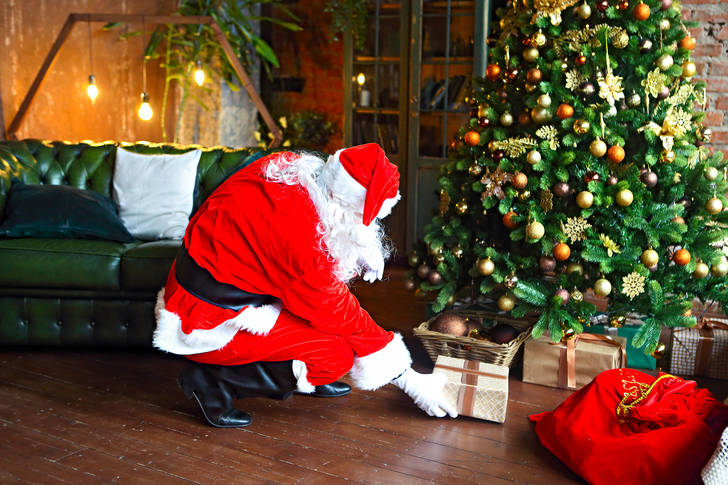 Santa Claus puts gifts under the tree