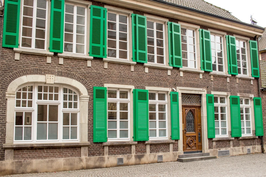 Fasad av ett gammalt hus med gröna fönsterluckor