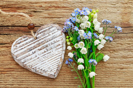 Forget-me-nots and lilies of the valley on a wooden background