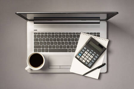 Сив лаптоп, бележник и калкулатор