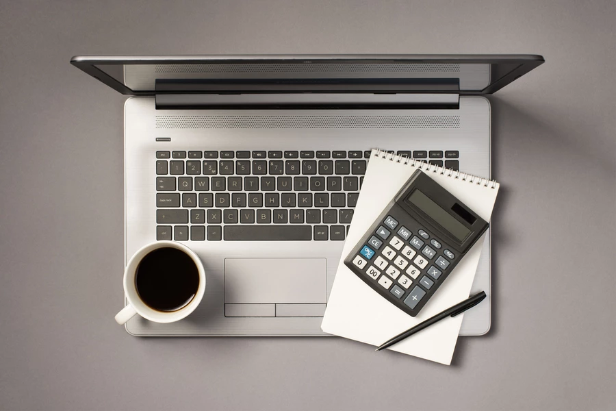 Computadora portátil, libreta y calculadora grises