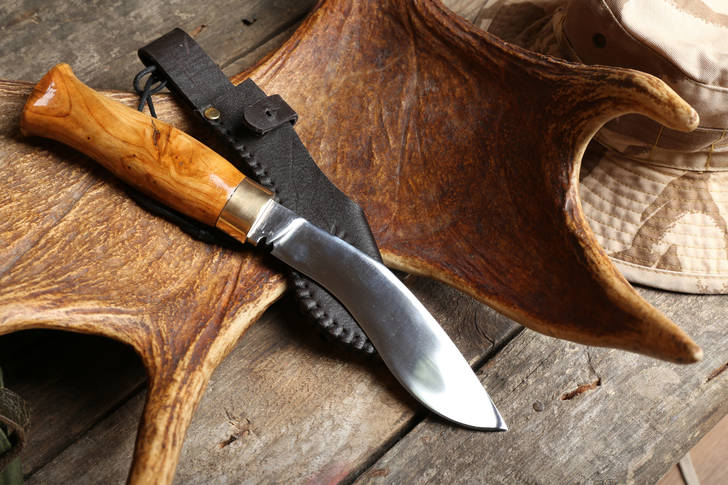 Cuchillo de caza y trofeo en mesa de madera