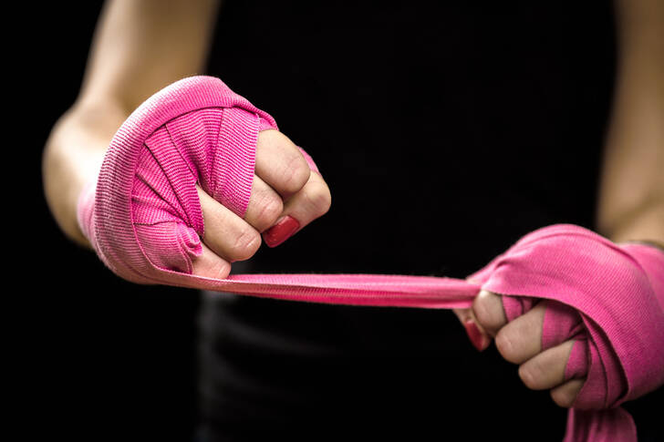 Mãos com bandagens elásticas cor-de-rosa