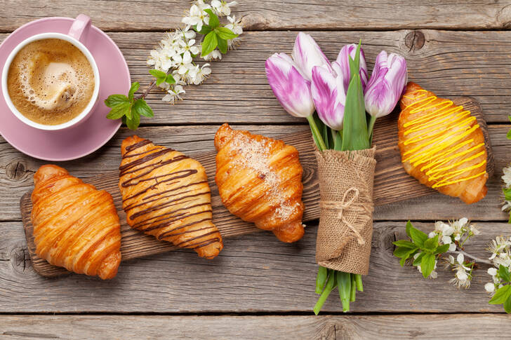 Croissants, Kaffee und ein Strauß Tulpen