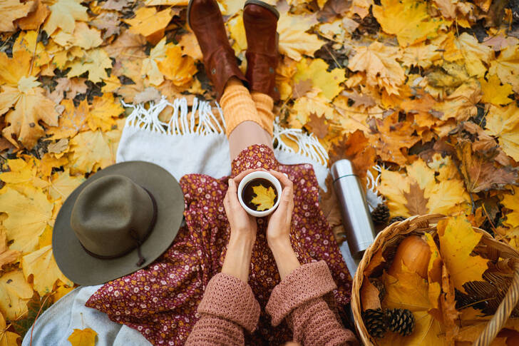 Girl in autumn forest drinking tea