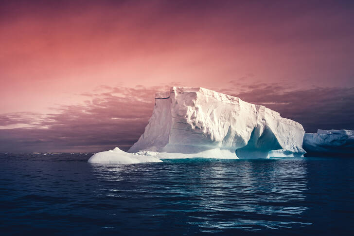 An iceberg against the sunset sky