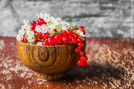 Red and white currants in a wooden bowl