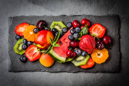 Ягоди та фрукти на чорній тарілці