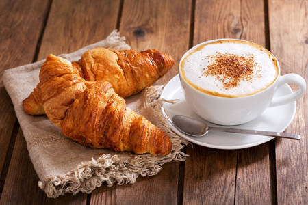 Cappuccino with croissants on a wooden table