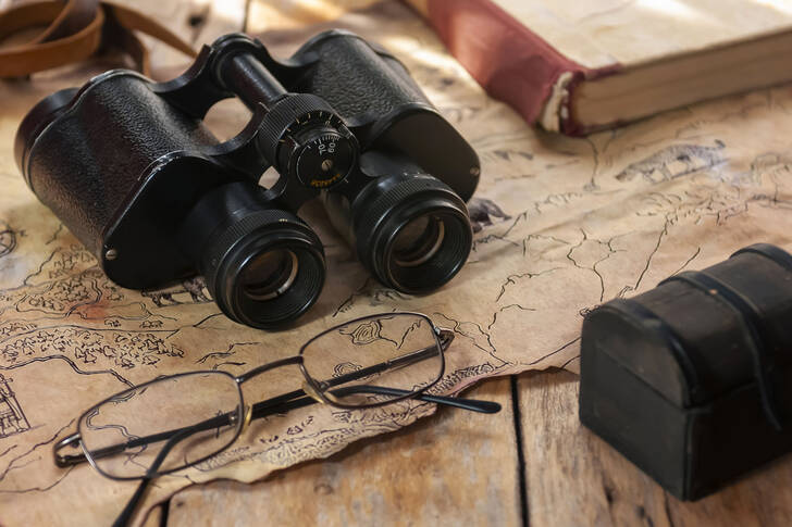 Binoculars and glasses on an old map