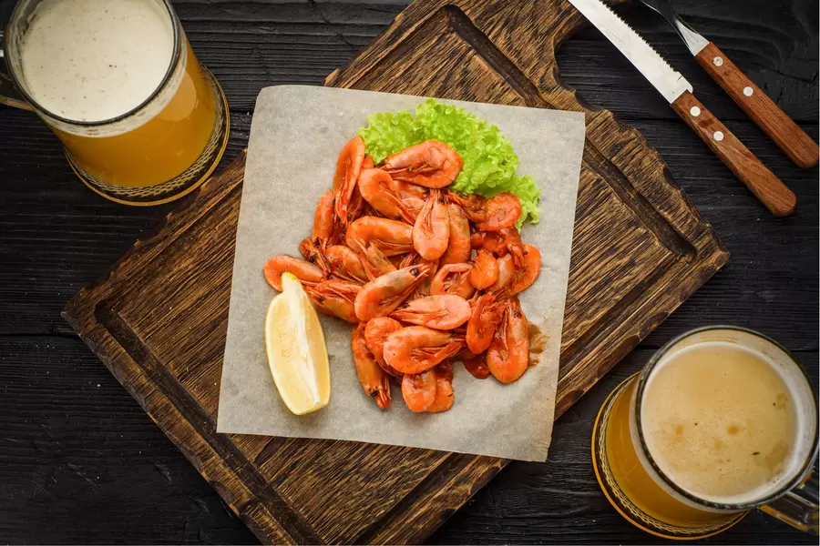 Pivo i prženi škampi na drvenoj dasci