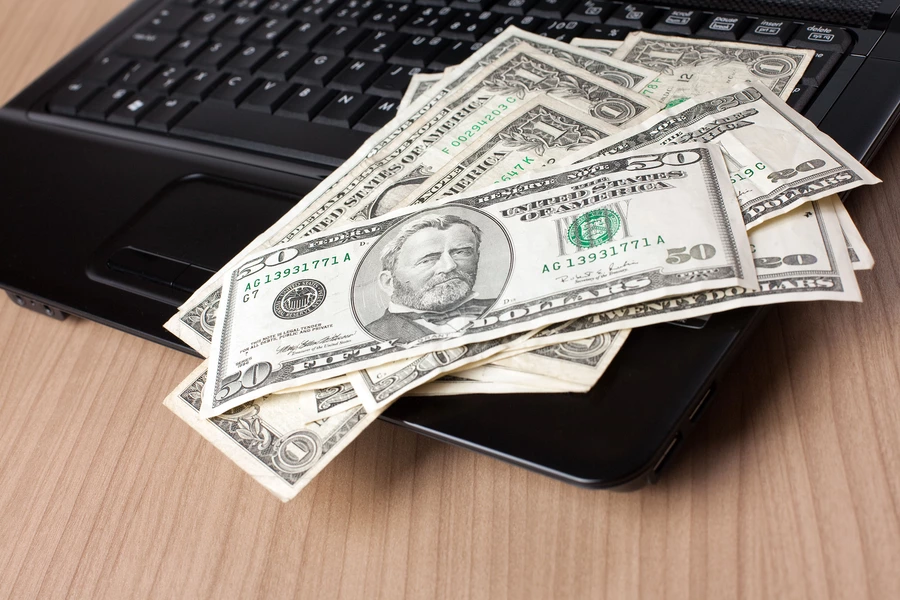 Billetes de dólar sobre el teclado de un portátil