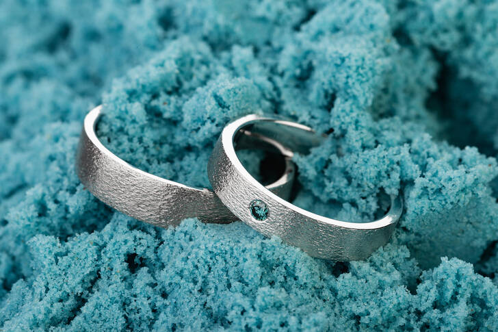Anéis de casamento na areia azul