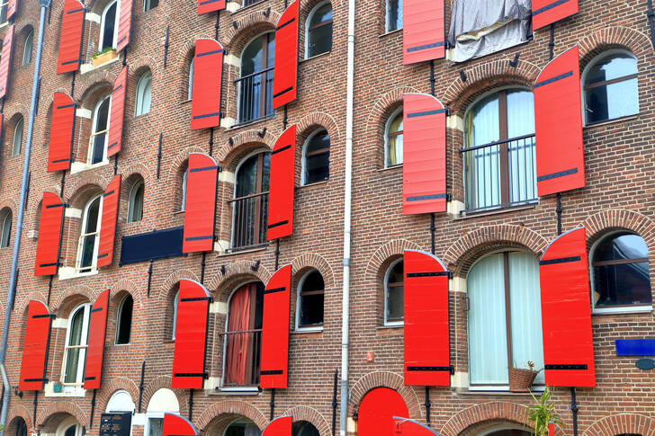 Fasáda domu s červenými okenicemi