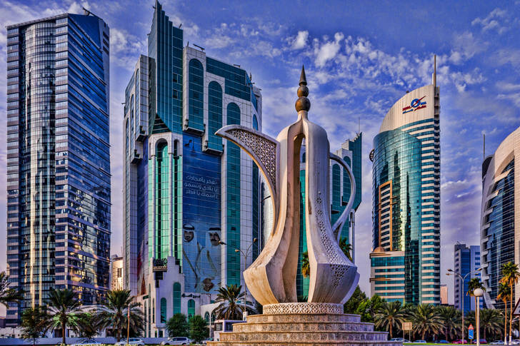 Escultura con el telón de fondo de los rascacielos en Doha