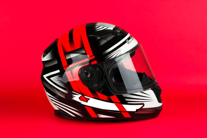 Motocyklová helma na červeném pozadí