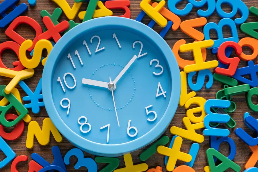Uhr auf dem Hintergrund von bunten Buchstaben