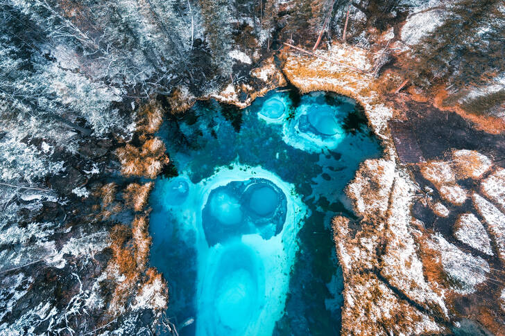 Niebieskie jezioro gejzerów w jesiennym lesie