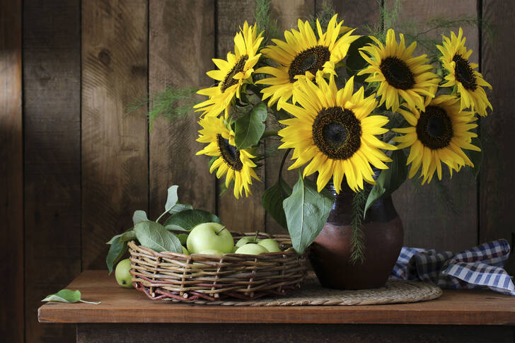 Sunflowers and green apples in a basket